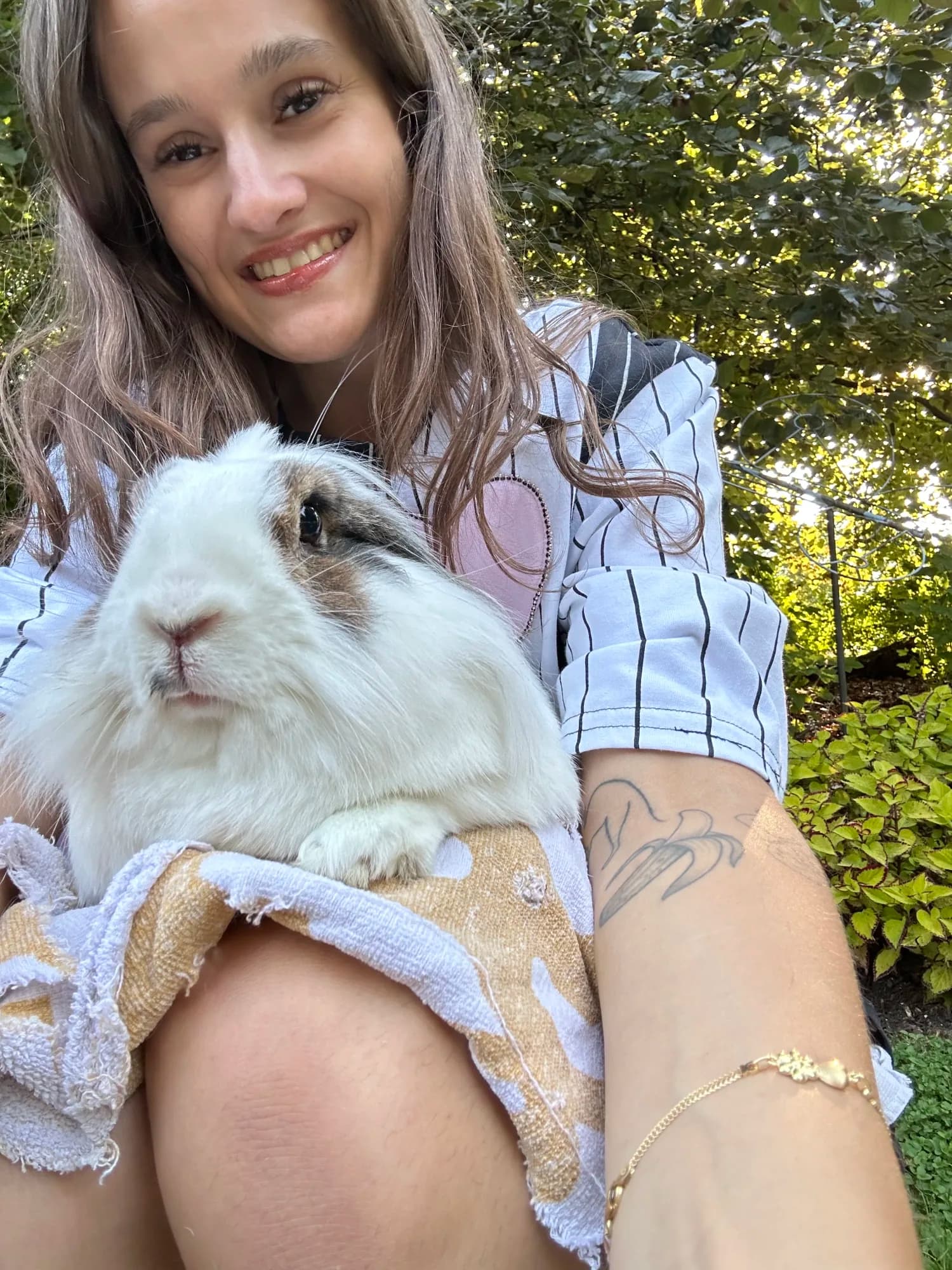 The Little Rascals owner smiling beside a fluffy white rabbit outdoors