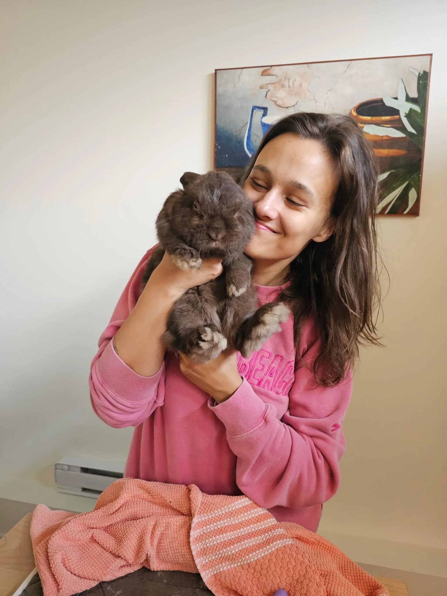 The Little Rascals owner smiling while safely supporting a dark grey rabbit